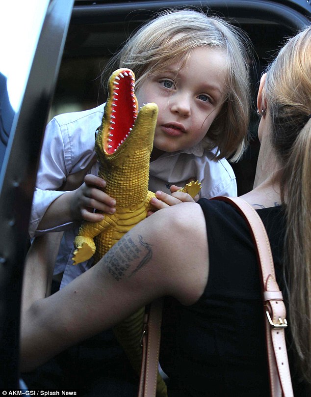 Off we go: Angelina lifted son Knox into the car as he clutched onto his dinosaur