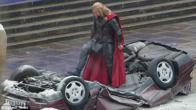 Super strength: Chris Hemsworth stands on top of a crushed car in an amazing display of his character's might