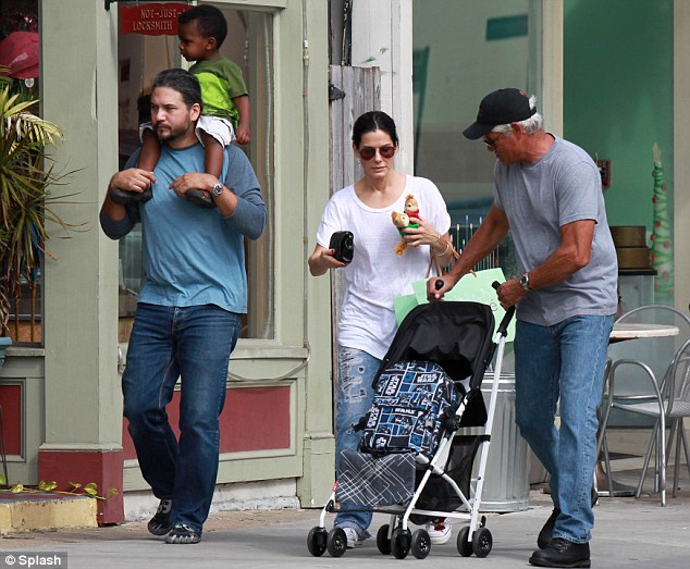 Sandra and the chipmunks: Ms Bullock juggled a couple of cuddly toys as she walked through New Orleans with her bodyguard and a mystery man carrying son Louis 