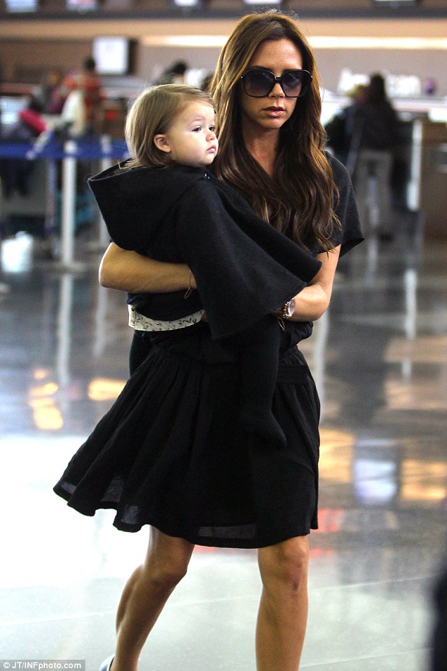 Mummy's little jetsetter: Victoria teamed Harper's jacket with a white floral dress and black tights
